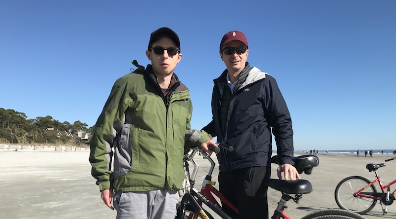 Two men standing in front of a bicycle