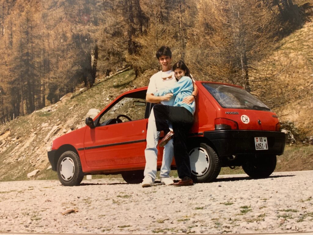 Young couple standing in front of red car