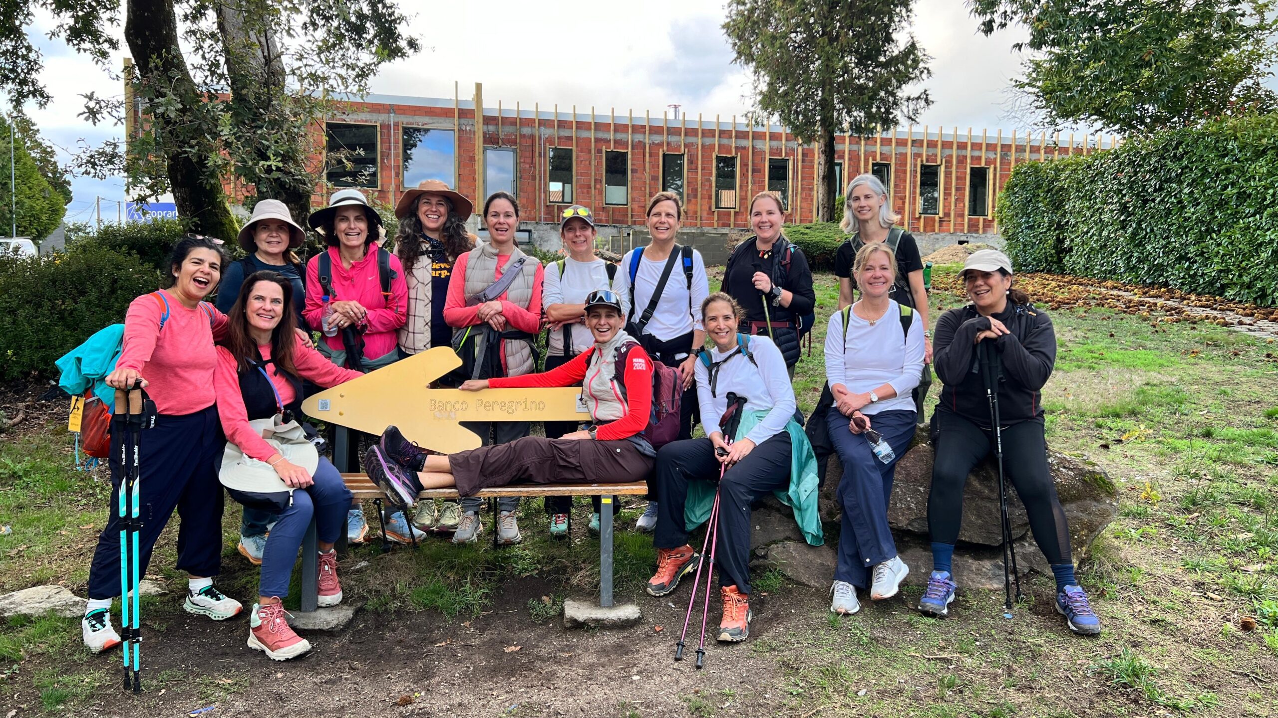 Fourteen women posing around a big yellow arrow