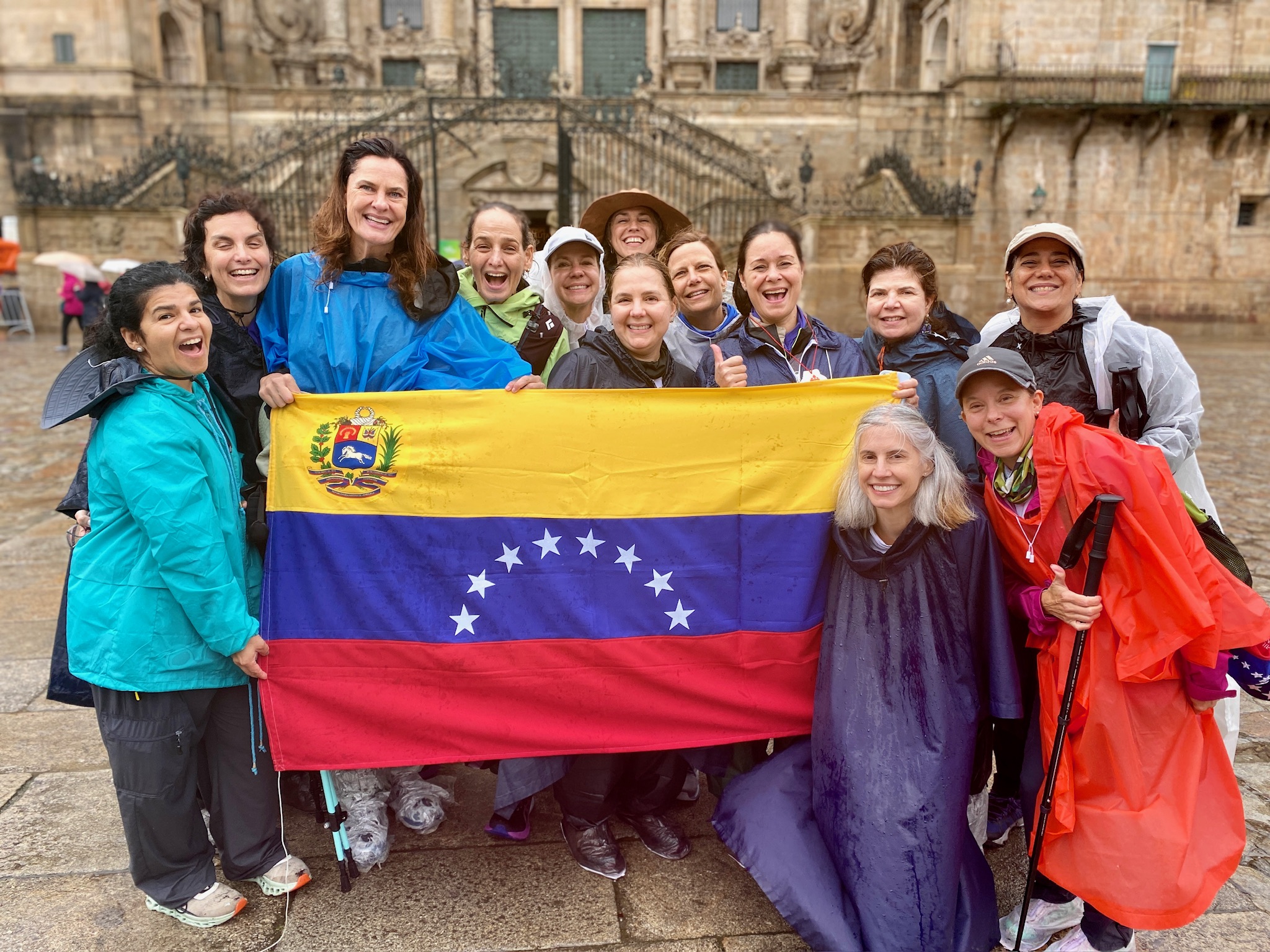 Women posing in front of a cathedral holding a Venezuelan flag