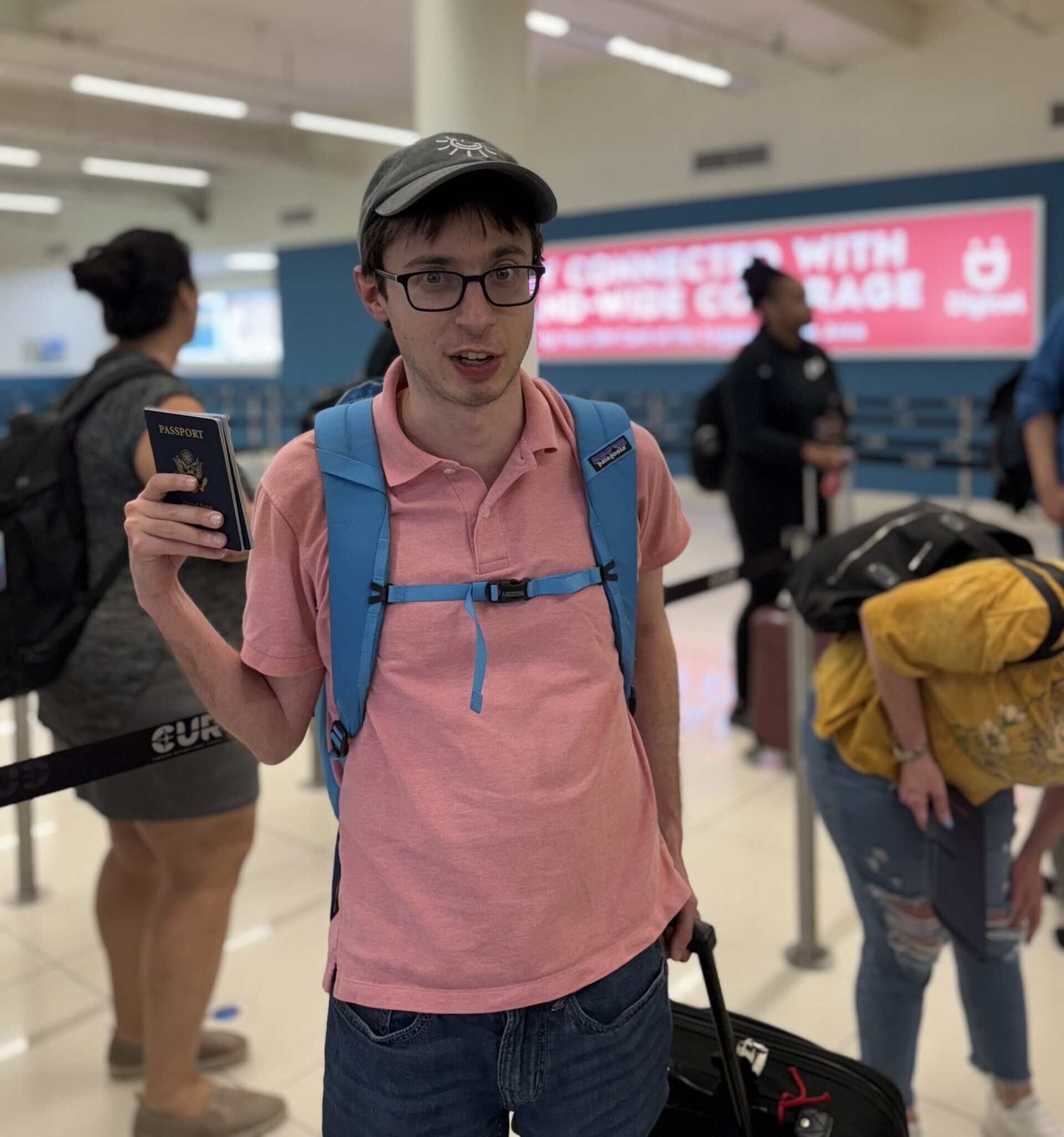 Man with glasses, and hat holding passport at the airport