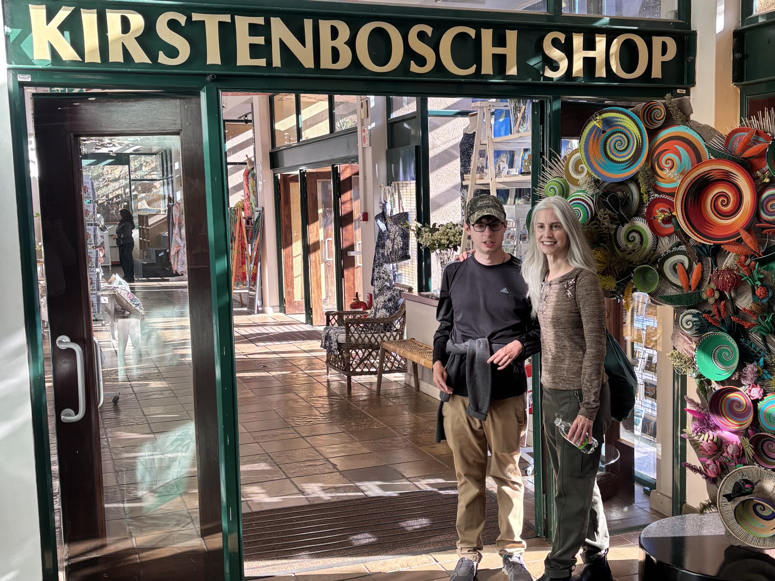 Man and woman standing at door with sign that reads Kirstenbosch